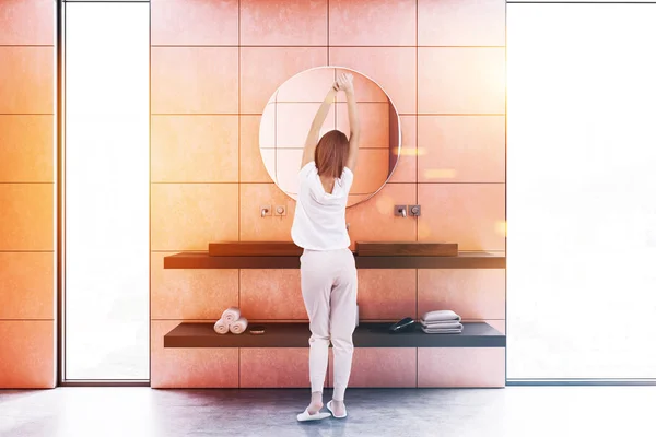 Wooden double sink on black shelf with a round mirror hanging above it in a luxury orange wall loft bathroom interior. Luxury lifestyle and spa. Hotel. Woman in pajamas 3d rendering toned image