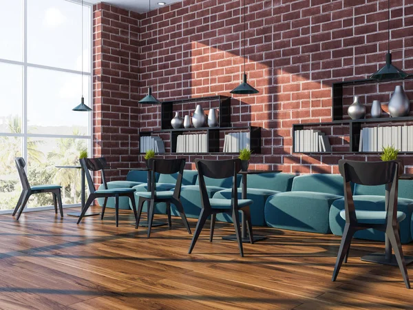 Brick wall coffee shop corner with a wooden floor, large windows with a tropical view, blue couches, chairs and black tables. Bookshelves on the walls. 3d rendering mock up
