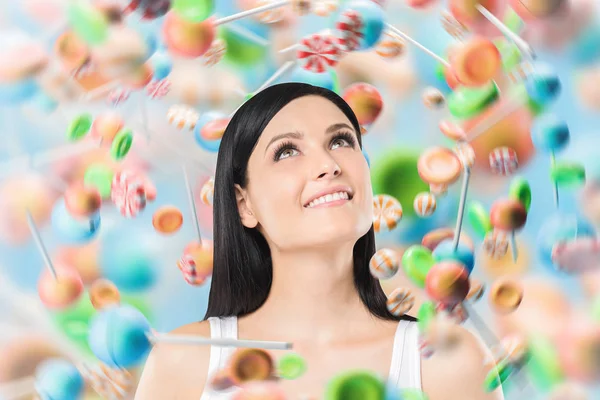 Happy young woman with black hair looking up over colorful orange blue and green lollipops background. Concept of little joys, guilty pleasures and sweets addiction. 3d rendering mock up