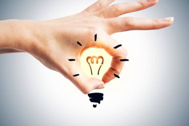 Kadın el Sarı parlak içinde gri duvar arka plan üzerinde çizilmiş ampul ile ok işaretiyle gösterilen. Fikir kavramı