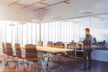 Afrika kökenli Amerikalı işadamı bir panoramik konferans salonundaki beyaz duvarları, uzun ahşap bir masa ve siyah sandalye ile ayakta. İletişim ve takım çalışması kavramı. 3D render sahte tonlu görüntü