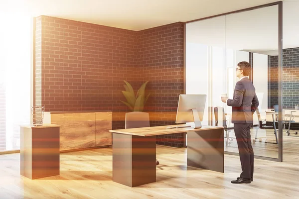 Office of a company manager with black brick walls, a wooden floor, a stylish table and a potted plant. Businessman thinking. Side view. 3d rendering mock up toned image.