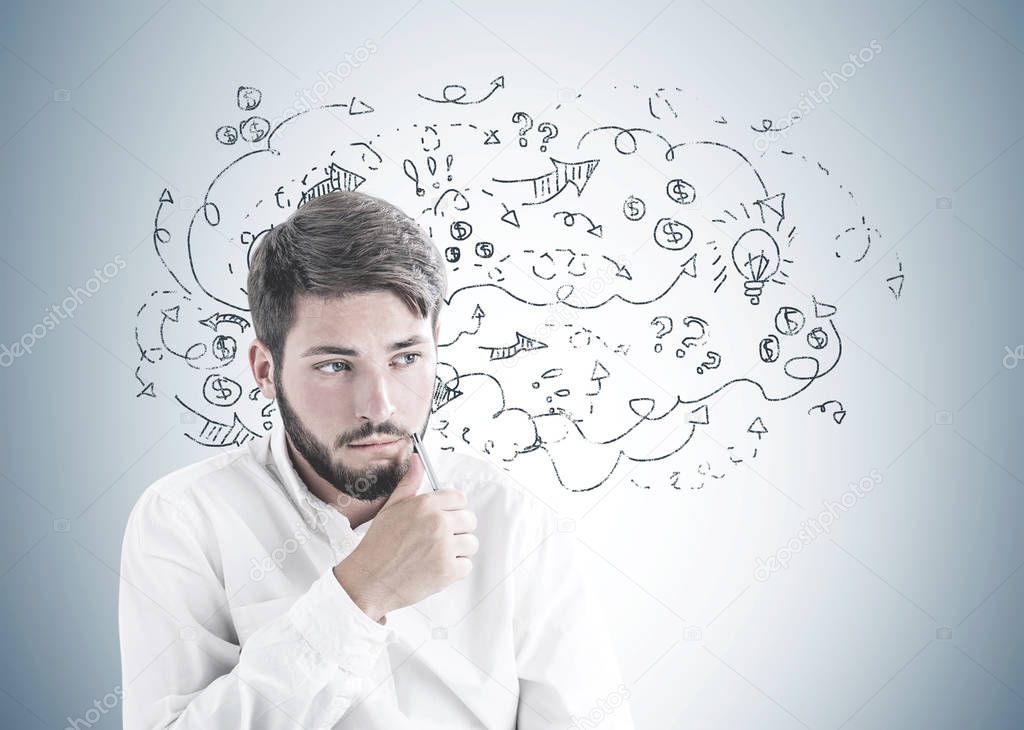 Troubled young bearded caucasian businessman wearing a white shirt sitting with pen near his face and thinking looking sideways. A gray wall background with question marks and arrows. Idea