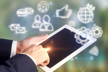İşadamı tablet bilgisayarınızla çalışmak ve onun perde dokunmadan koyu takım elbise eller. Bulanık yeşil ile mavi arka plan parlayan sosyal medya simgeler. Çift tonlu görüntü pozlaması