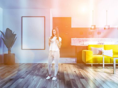 Parlak sarı kanepe ve poster çerçevesi kadar dikey sahte ile modern stüdyo düz oturma odasında smartphone ayakta olan kadın. Mermer mutfak arka planda. 3D render tonlu görüntü