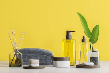 Şeffaf şişe sahte konteynırları yukarı beyaz sabun ve spa ürünleri ile. Aroma sopa ve beyaz masa üzerinde gri havlu yığını. Sarı duvar arka plan. Gevşeme ve öz bakım kavramı. 3D render