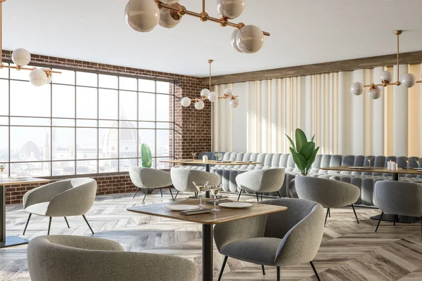 Interior of stylish restaurant with brick walls, wooden floor, gray comfortable couches and armchairs and wooden tables. Stylish lamps and European cityscape from window. 3d rendering copy space