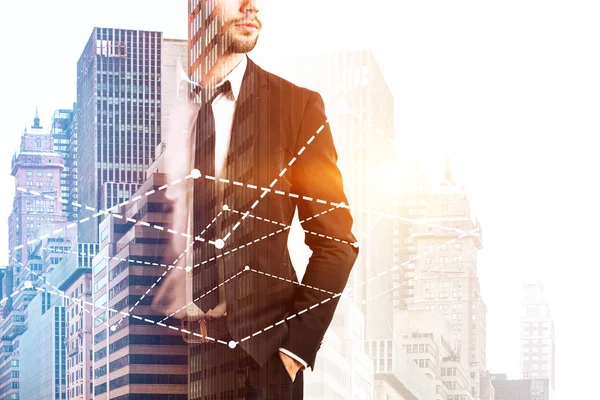 Unrecognizable bearded businessman in suit and tie standing with hands in pockets against graphs over morning cityscape. Stock market and fintech concept. Toned image double exposure copy space