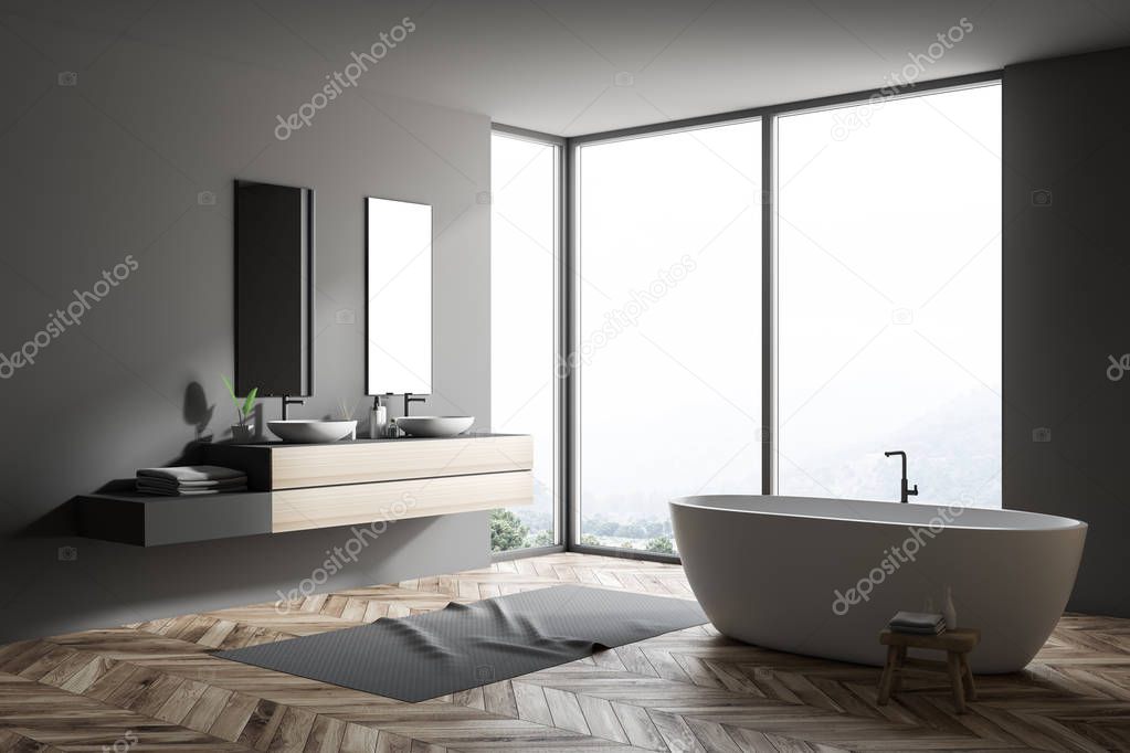 Stylish gray bathroom interior with wooden floor, gray rug, window with forest view, wooden wall, big bathtub, and double sink with vertical mirrors. 3d rendering copy space