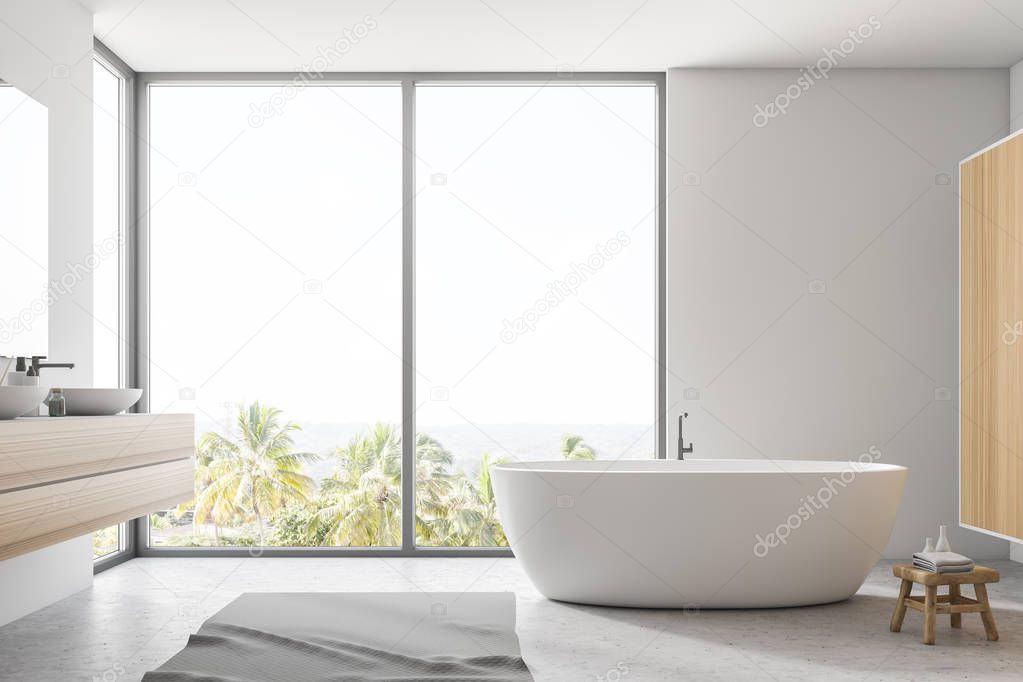 Stylish white bathroom interior with concrete floor, gray rug, window with tropical view, big bathtub, and sink with vertical mirror. 3d rendering copy space