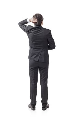 Isolated full length portrait of young caucasian businessman with black hair wearing a dark suit and scratching his head thinking about strategy of company. clipart