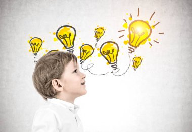 Beyaz gömlek ve koyu mavi kot pantolon giyen ve yukarı doğru seyir sarışın saçlı sevimli küçük beyaz çocuk yan görünüm. Sarı Işık Ampüller kroki beton duvar