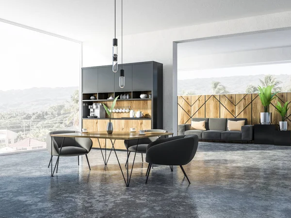 Corner of pranoramic studio apartment with kitchen corner, a square table with gray armchairs and sofa with cushions. Tropic view scenery in the window. 3d rendering