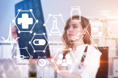 Bulanık kırmızı saçlı kadın doktor röntgen ofisinde bakarak. Parlayan tıbbi simgeler sürükleyici arabirimi. Çift tonlu görüntü pozlaması
