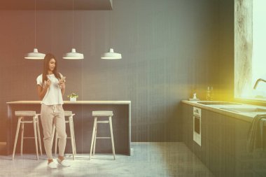 Beton zemin, büyük pencere ve gri gri mutfak iç ve ahşap duran genç kadın mutfak tezgahı. Bar tabureleri ile. Çift tonlu görüntü pozlaması