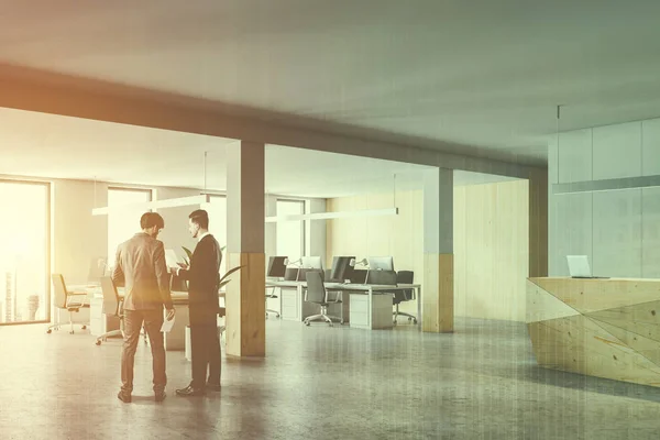 Two business partners discussing company issues in office hall with wooden reception desk and glass walls. Toned image double exposure