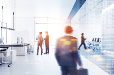 İş adamları ile panoramik pencerelere, beyaz bir ofiste yürüyüş duvarlar beyaz ve açık yer alan Bilgisayar masaları ile. Tonlu görüntü çift pozlama bulanık