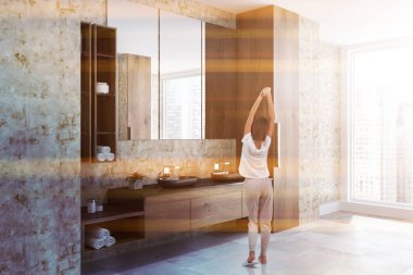 Lüks çatı banyo ahşap duvarlar, ahşap ve beyaz tezgah üzerinde duran çift lavabo ile köşesine Rulo havlu ve kremler ile temizleyelim. Genç Kadın pijama. Tonlu görüntü