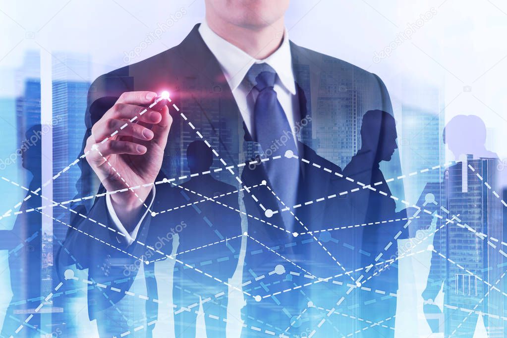Unrecognizable young businessman drawing graphs with glowing pen. Business team and cityscape background. Toned image double exposure