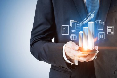 Tanınmayan işadamı ile çubuk grafik ve Internet simgeleri arayüzü ve hologram büyüyen akıllı telefon tutarak el. Merhaba teknoloji kavramı. Çift tonlu görüntü pozlaması