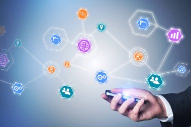 Tanınmayan işadamı gri duvarının yakınında smartphone ayakta tutan el. Bulut teknoloji arabirimi ön plan. Çift tonlu görüntü pozlaması.