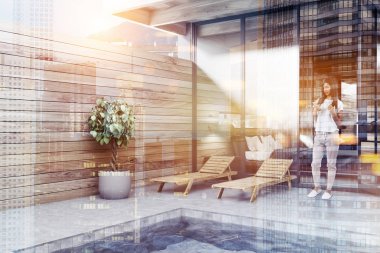 Özel havuz ahşap duvarlar, güverte sandalyeleri, bir pot ve arka odada bir ağaçta köşesinde. Kadın ile smartphone. Lüks yaşam tarzı kavramı. Çift tonlu görüntü pozlaması