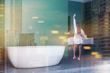 Yeşil duvarlar, beton zemin, beyaz küvet ve yuvarlak aynalı lavabo ile modern banyo köşede duran kadın. Çift tonlu görüntü pozlaması