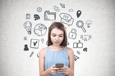 Uzun sarı saçlar smartphone iki eliyle tutarak ve ekrana bakarak mavi elbise giyen genç kadınla. Internet simgeleri ile beton duvar