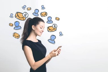 Onu smartphone ekran ayakta beyaz duvar ile e-posta kutsal kişilerin resmi yanında bakarak siyah elbiseli gülümseyen iş kadını. Yukarı alay