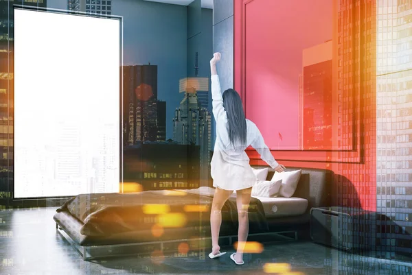 Woman in nightgown in minimalistic bedroom interior with gray and red walls, concrete floor, master bed with bedside tables and cityscape window. Toned image double exposure