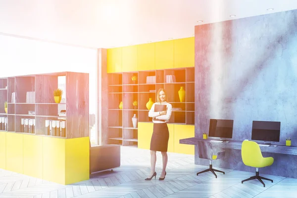 コンクリートの壁 白の木製の床 黄色と木製の本棚 それをコンピューターのモニターで長いテーブルでスタート アップ オフィスの金髪女性の実業家 トーンのイメージ — ストック写真