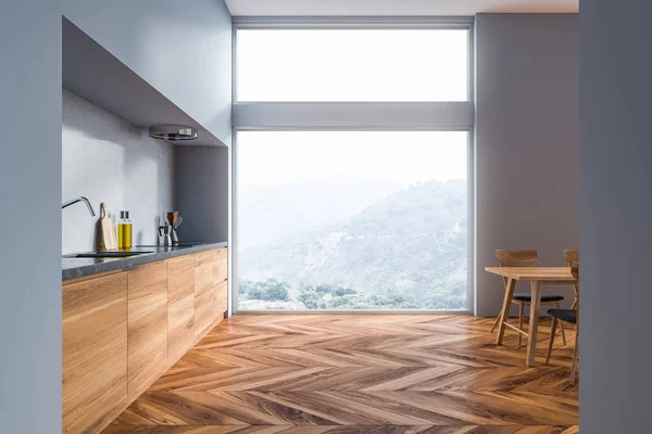 Interior of modern kitchen with gray walls, wooden floor, gray and wooden countertops, a table with chairs and loft window. 3d rendering