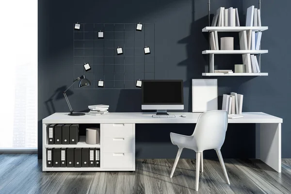 Interior of cozy home office with dark gray walls, wooden floor, neat table with computer on it and bookshelves. Small mock up photos on the wall. 3d rendering
