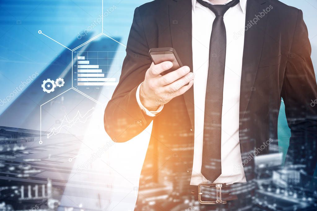 Unrecognizable businessman looking at his smartphone screen standing over cityscape background with infographics drawing. Toned image double exposure.