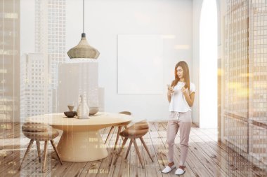 Modern yemek odası iç beyaz duvarlar, ahşap zemin, vazolar ve poster kadar dikey sahte ile yuvarlak masa ile akıllı telefon olan kadın. Çift tonlu görüntü pozlaması