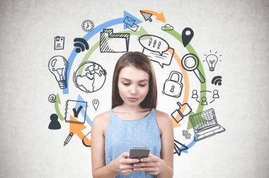 Onu smartphone ekran ayakta bilgisayar ve internet simgeler ve renkli oklar üzerinde çizilmiş beton duvar arka plan yakınındaki bakarak mavi elbiseli Genç kadın.
