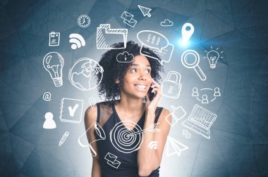 Afrikalı-Amerikalı kadın telefon ayakta beyaz bilgisayar ile koyu gri duvarının yakınında ve Internet çizim söz gülümseyerek. Çift tonlu görüntü pozlaması