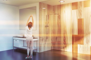 Gri ve ahşap duvarlar, modern banyo köşede duran kadın büyük kare ayna ile lavabo ve duş kabini. Tonlu görüntü