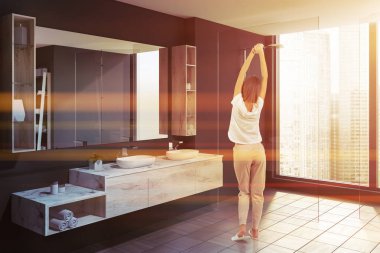 Gri duvarlar, modern banyo köşede duran kadın kat, beyaz çift lavabo ayakta ahşap tezgah ve duş çatı penceresi yakınındaki döşenir. Tonlu görüntü