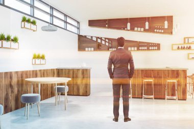 Beyaz ve ahşap duvarlar, modern bar iç ayakta işadamı yuvarlak ahşap masa, küçük gri sandalyeler ve tabureler olan ahşap çubuk. Şişe raflarda. Tonlu görüntü