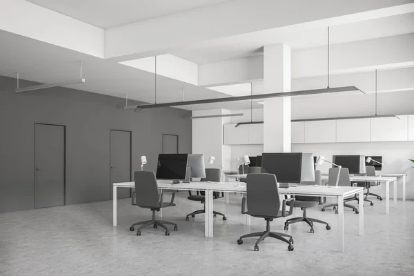 侧视图的开放空间办公室与白色的墙壁 混凝土地板 成排的电脑桌与桌面在他们 墙上的一排排门 — 图库照片
