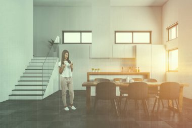 Modern mutfak ve yemek odası beyaz duvarlı kadında döşeli kat, beyaz dolapları, ahşap ve beyaz bar, gri sandalyeler ve merdiven ahşap masa. Çift tonlu görüntü pozlaması