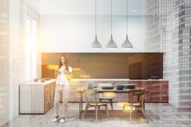 Kadın beyaz ve gri duvarlar, ahşap zemin ve ahşap ve beyaz mutfak tezgahı ile modern mutfak aletleri ve yemekler onlara inşa. Ahşap talbe sandalye ile. Çift tonlu görüntü pozlaması