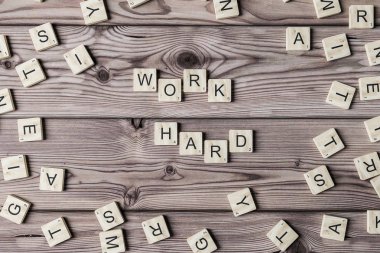 Work hard spelled from scrabble tiles lying on wooden table. Concept of hard work and success in life. 3d rendering clipart