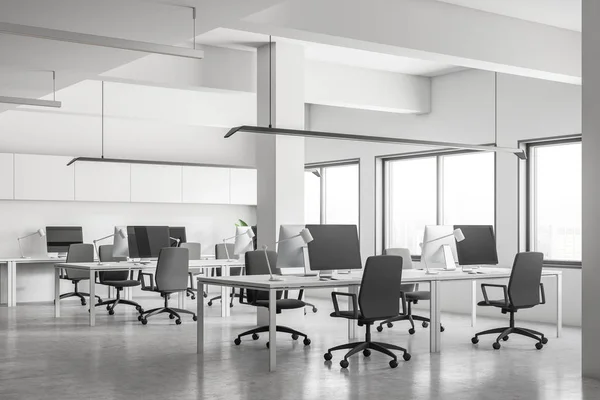 Industrial style office corner with white walls, rows of white tables with computers on them, concrete floor and columns. Small windows. 3d rendering