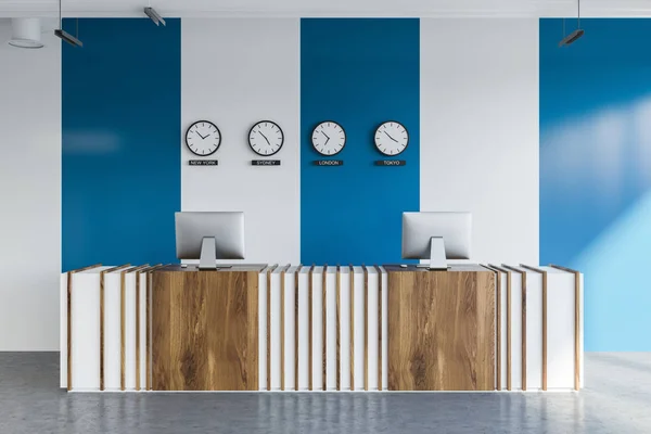 Front view of white and wooden reception desk with two computers on it standing in modern company office with white and blue walls and clocks with world time. 3d rendering