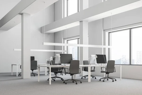 Corner of industrial style office with white walls, carpet on the floor and rows of computer tables with gray chairs standing near them. 3d rendering