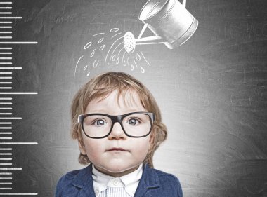Mavi takım ve blackboard bir cetvel ile yakın duran ve sulama Gözlük Sevimli küçük çocuk onu çizilmiş. Büyüme kavramı