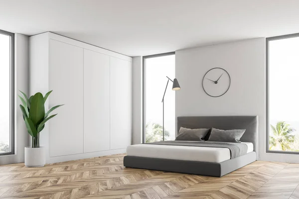 Corner of master bedroom with white walls, wooden floor, and master bed with clocks hanging above it. 3d rendering