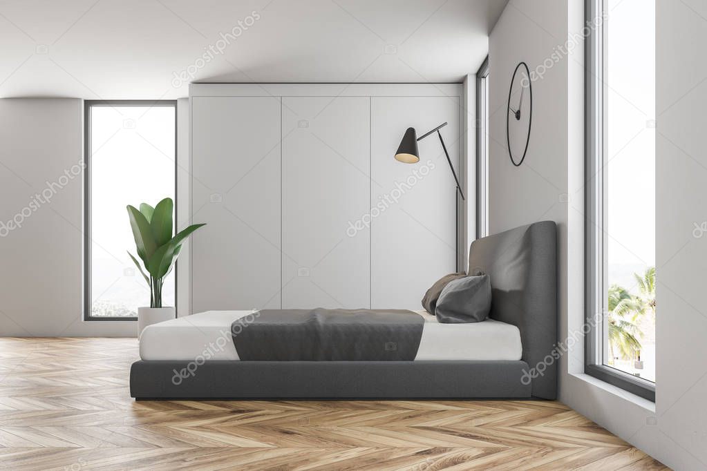 Side view of master bedroom with white walls, wooden floor, gray and white master bed and clocks hanging above it. 3d rendering